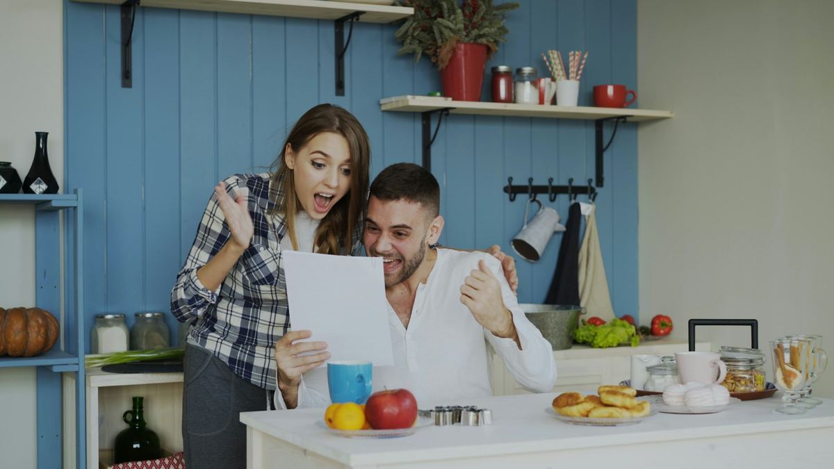 Ein Paar, das lachend gemeinsam einen ausgedruckten Bericht liest